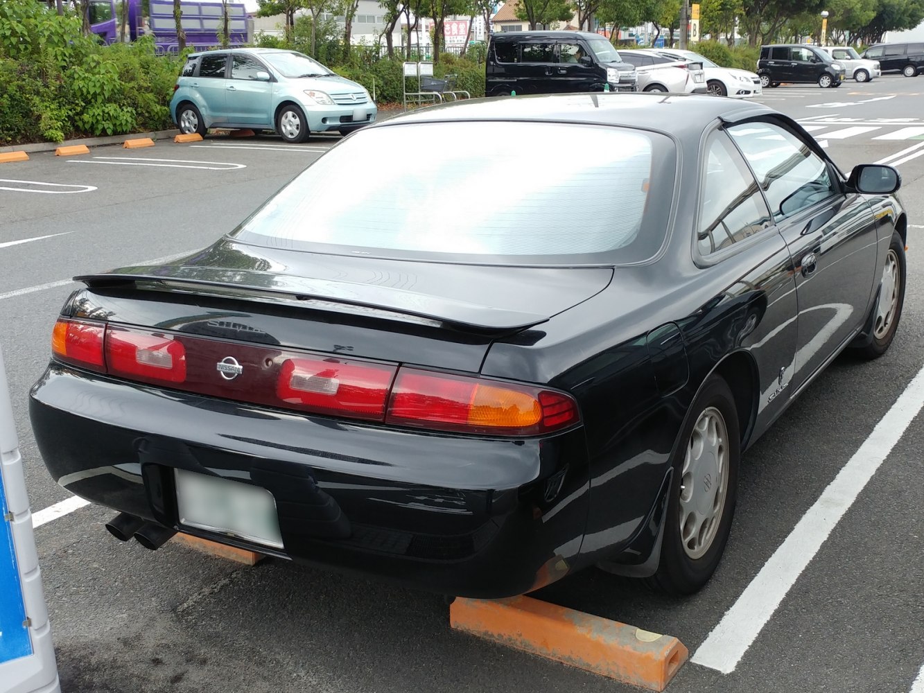 Rear view of a black coupe with spoiler and distinctive taillights.
