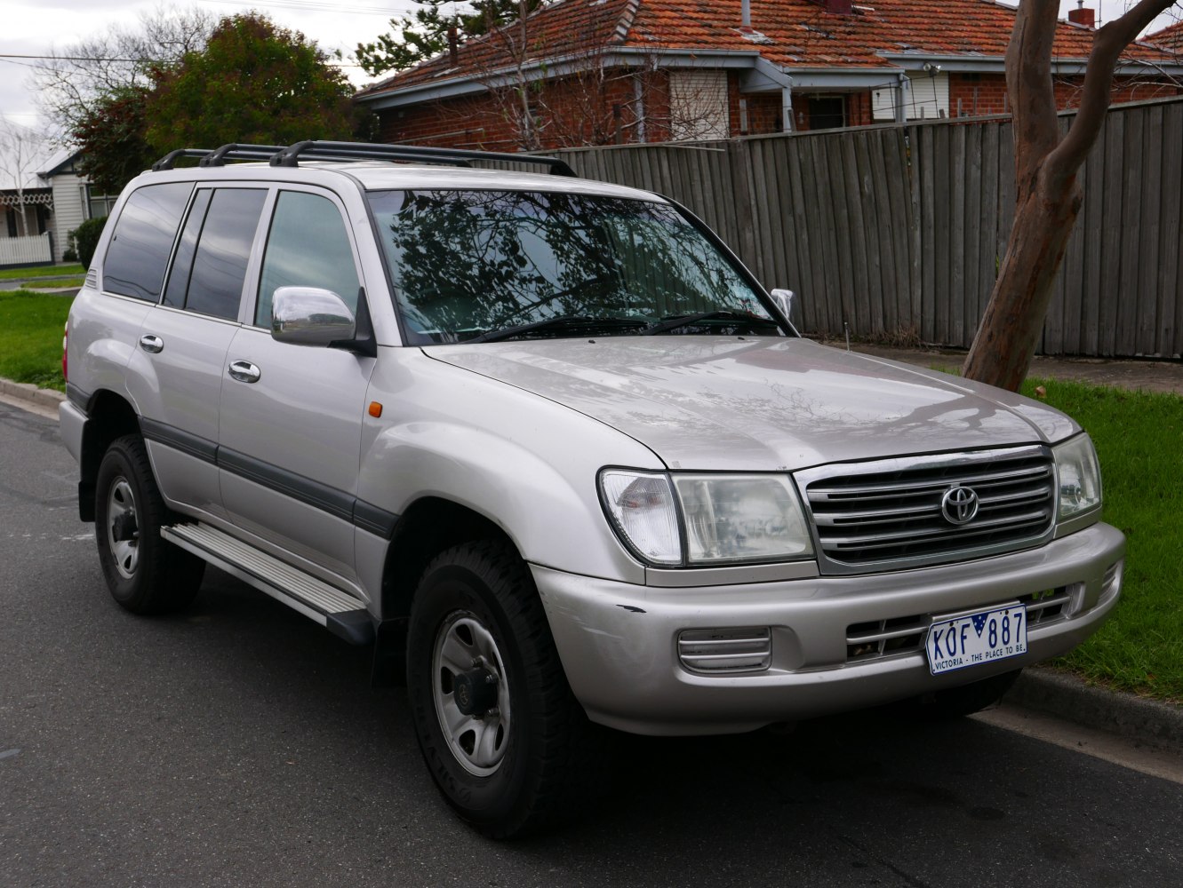 Front side view of silver large SUV with prominent grille and roof rails