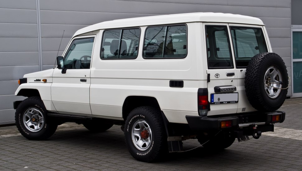 White SUV with rear-mounted spare tire and rugged, off-road tires