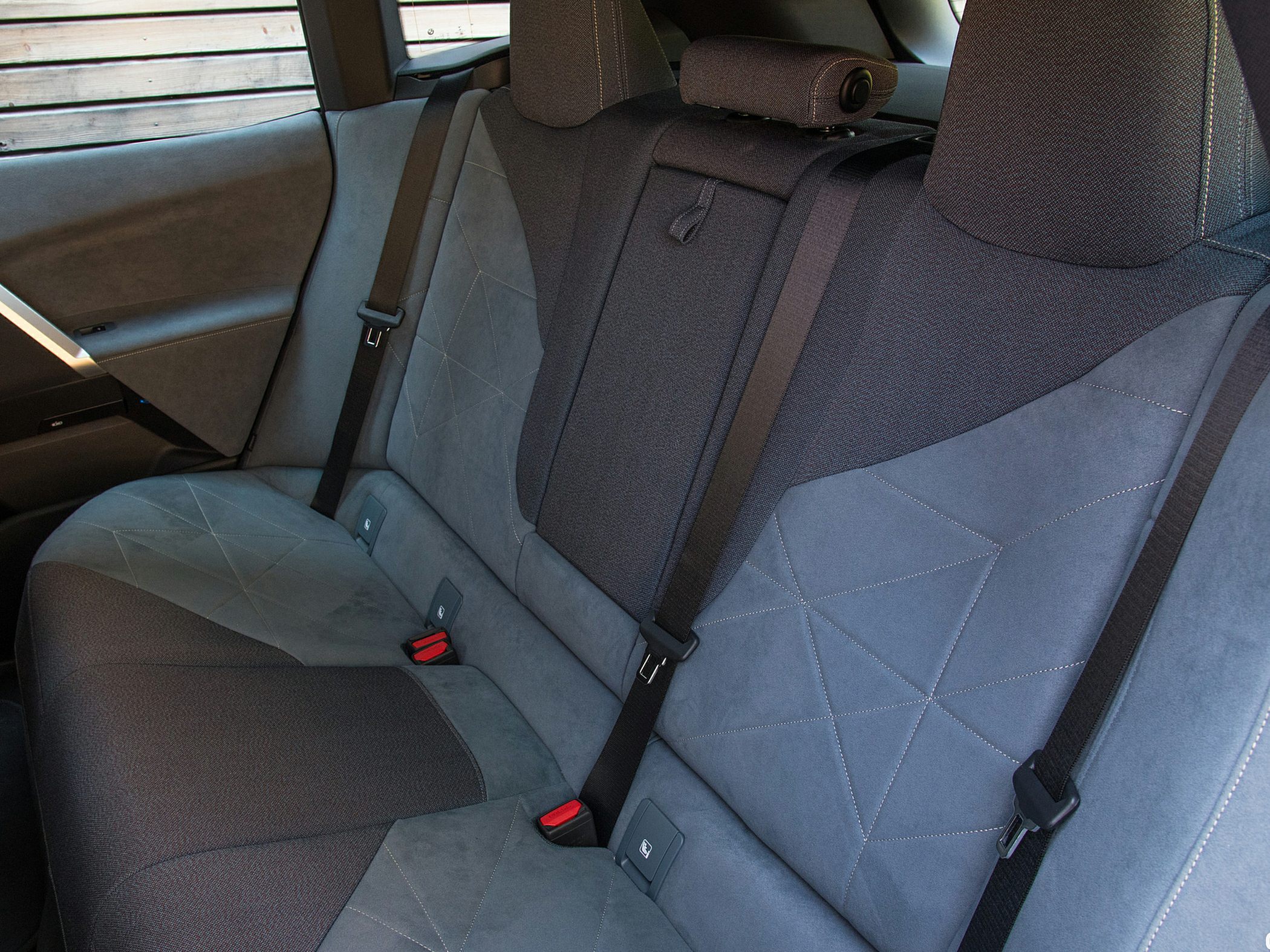 Rear seat upholstery with fabric and suede-like material, seat belts, and stitching detail
