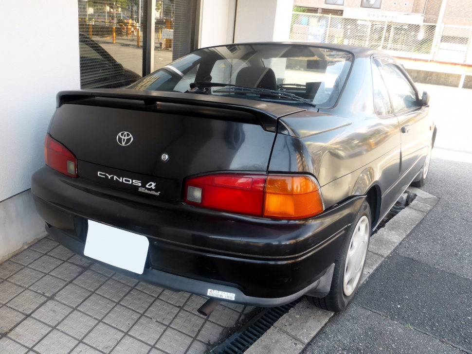Rear view with spoiler and distinct taillights of a compact coupe.