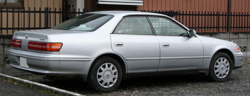 Silver sedan rear and side view with distinctive tail lights and wheel covers