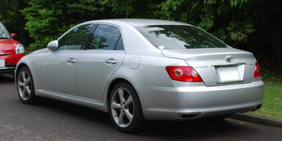 Silver sedan rear and side view with five-spoke alloy wheels and distinctive rear lights.