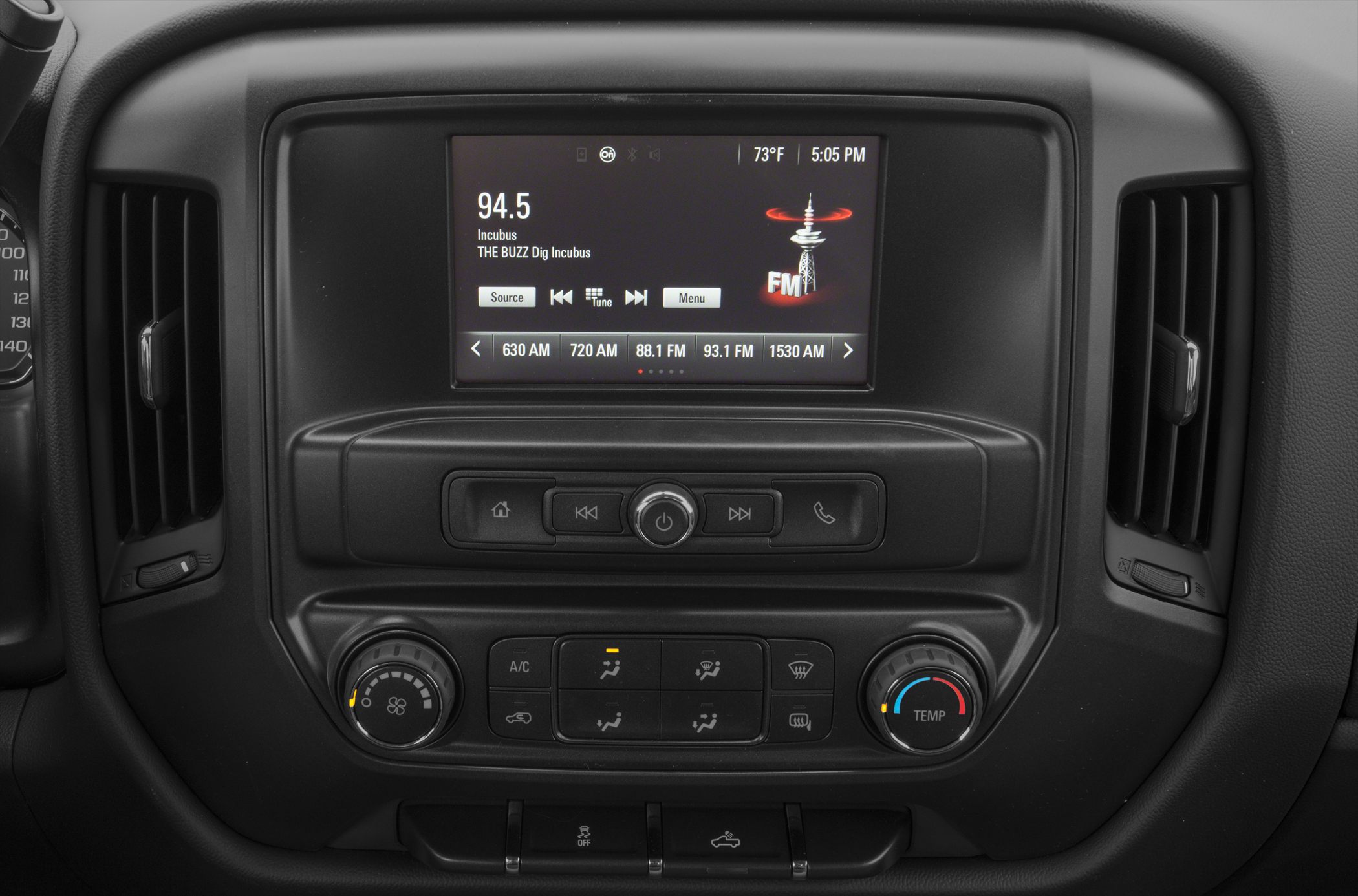 Infotainment screen and climate control knobs with air vents on dashboard