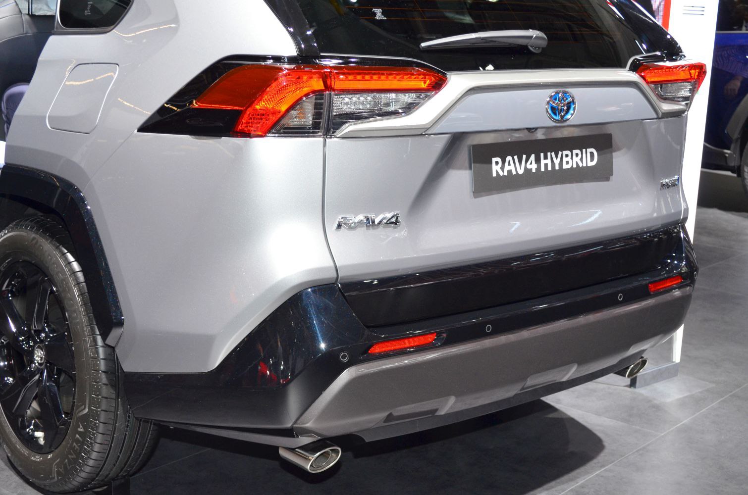 Rear of a modern SUV with hybrid badge, tail lights, and dual exhaust tips