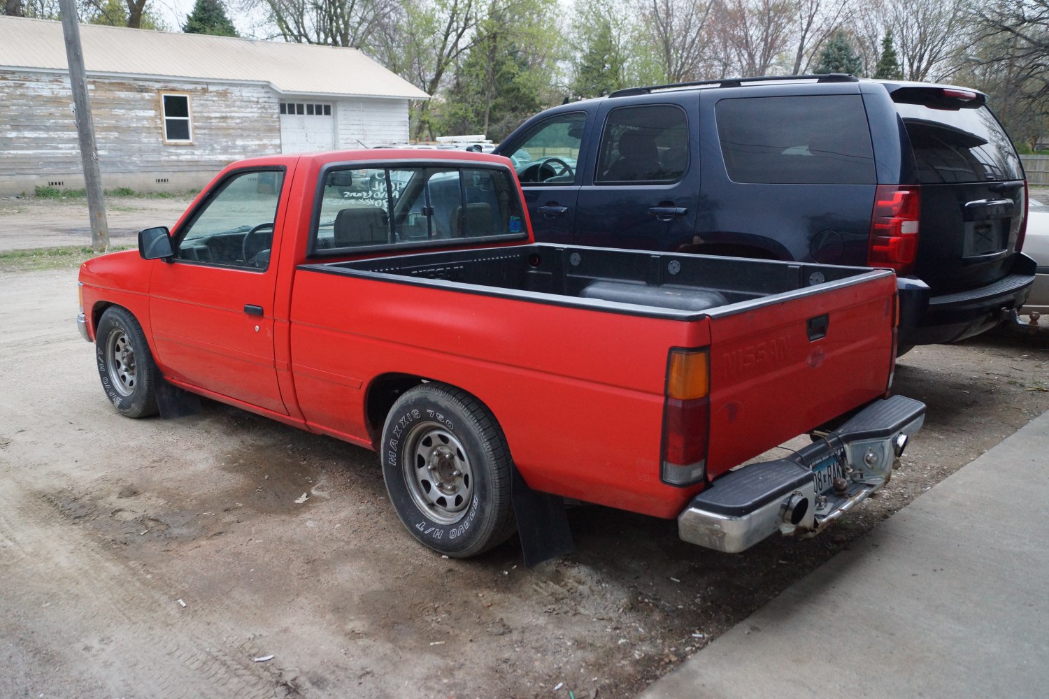 Red single cab pickup truck with open cargo bed and rear bumper hitch.