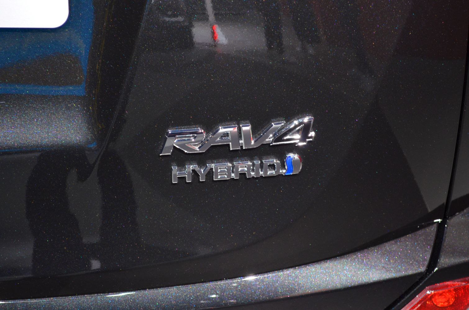 Close-up of RAV4 hybrid emblem on black metallic rear body