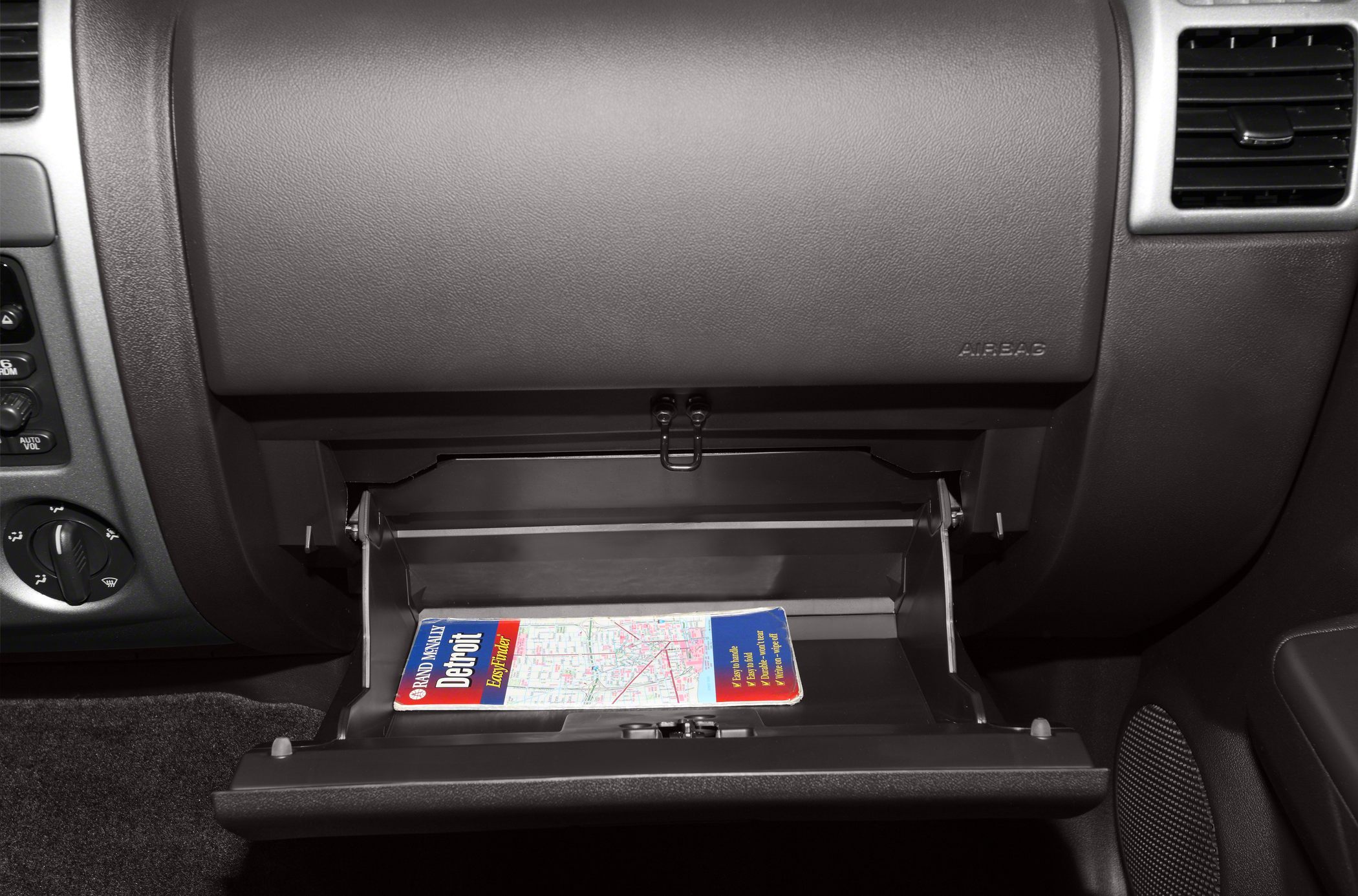 Open glove compartment with travel map inside vehicle cabin