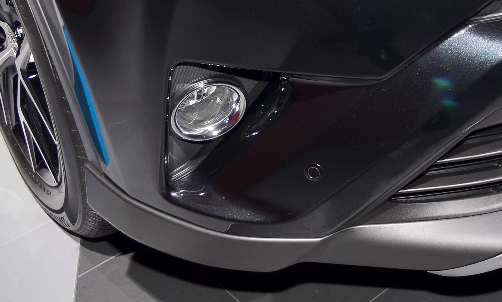 Close-up of front fog light and tire on a dark bumper