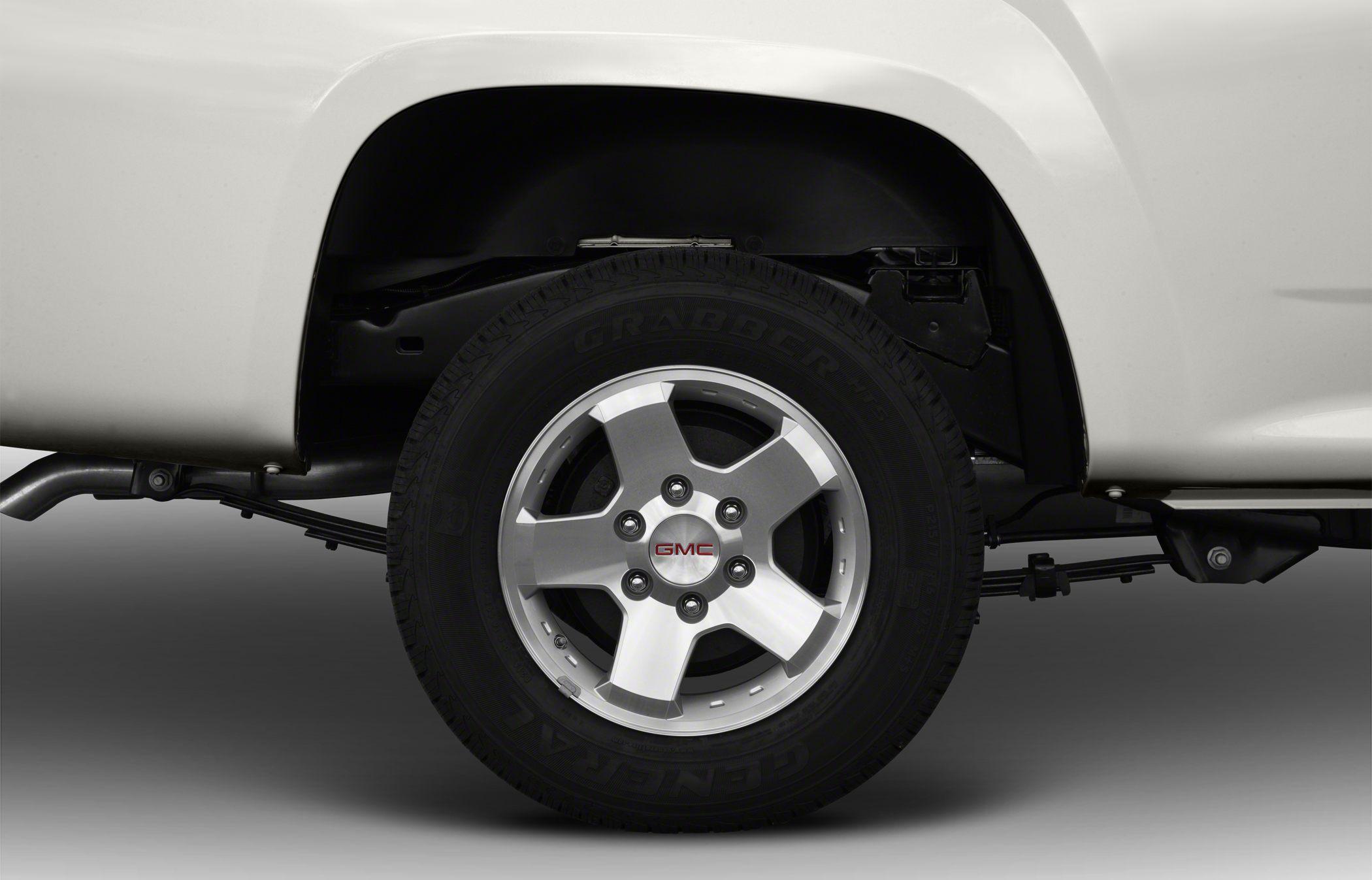 Close-up of five-spoke alloy wheel and leaf spring suspension.