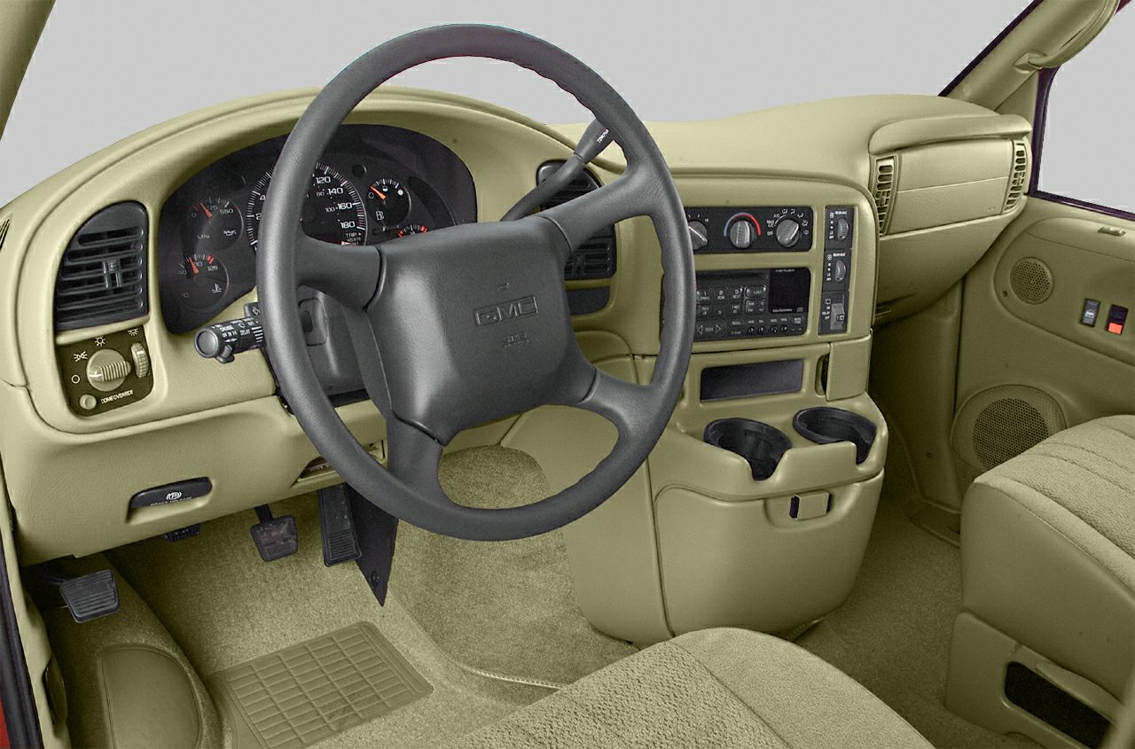 Beige dashboard and black steering wheel with cup holders and pedals