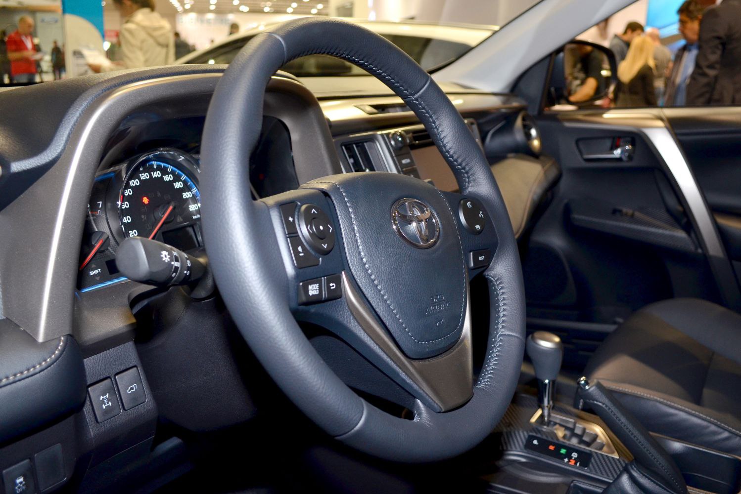 Steering wheel and dashboard with instrument cluster and control buttons.