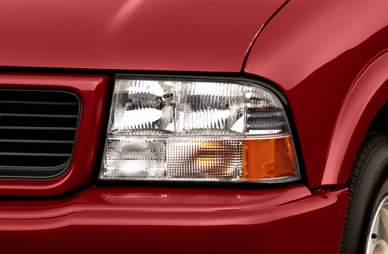 Close-up of a vehicle headlight and front grille with amber turn signal.