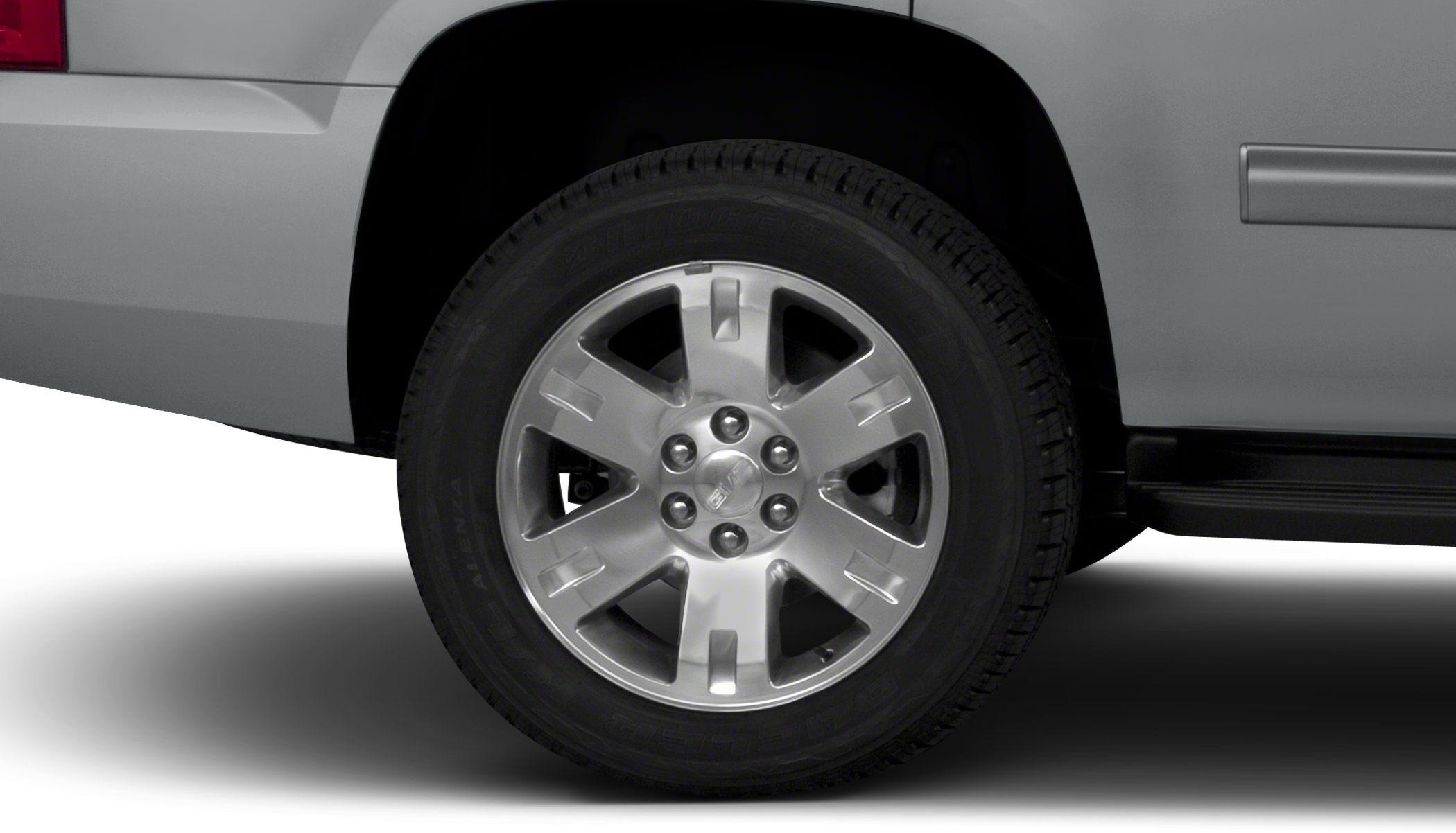 Silver alloy wheel with rugged tire tread on SUV.