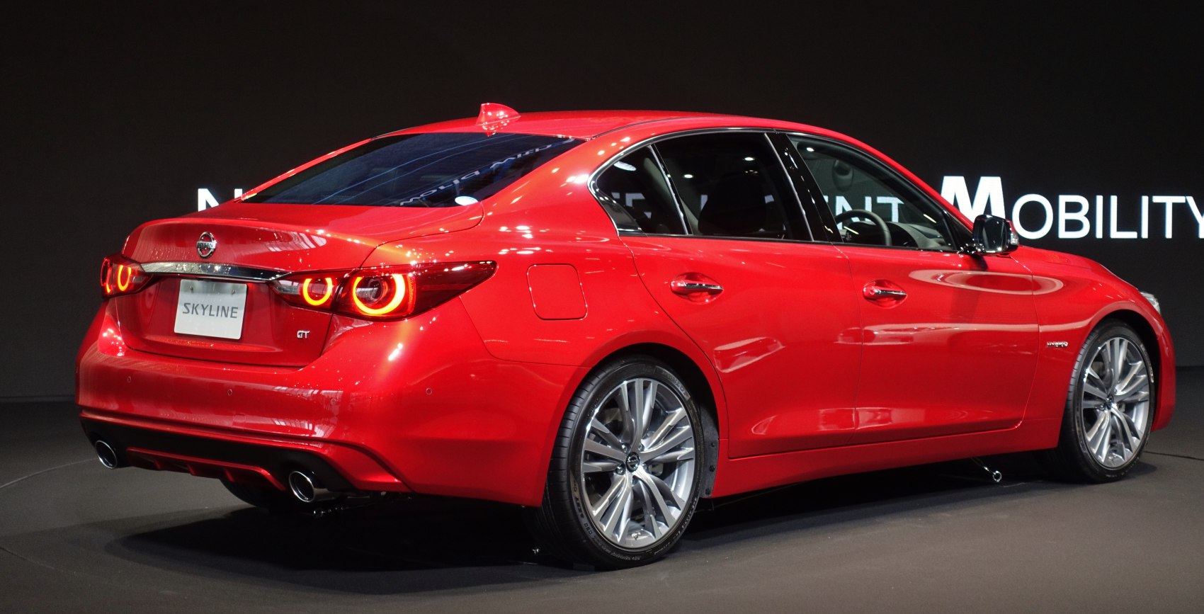 Red sedan rear-side view with circular LED taillights and alloy wheels