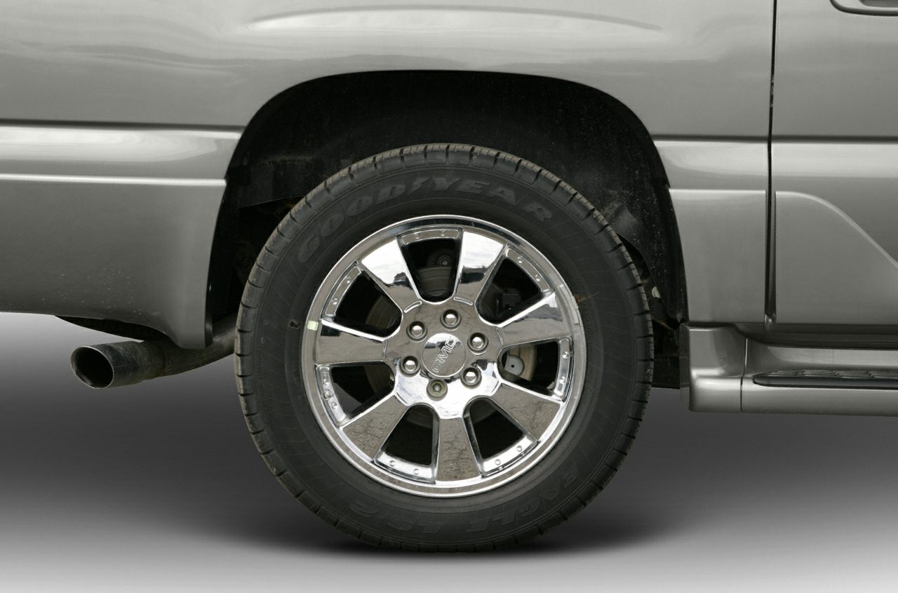 Chrome alloy wheel with Goodyear tire and visible exhaust pipe on vehicle's rear side.