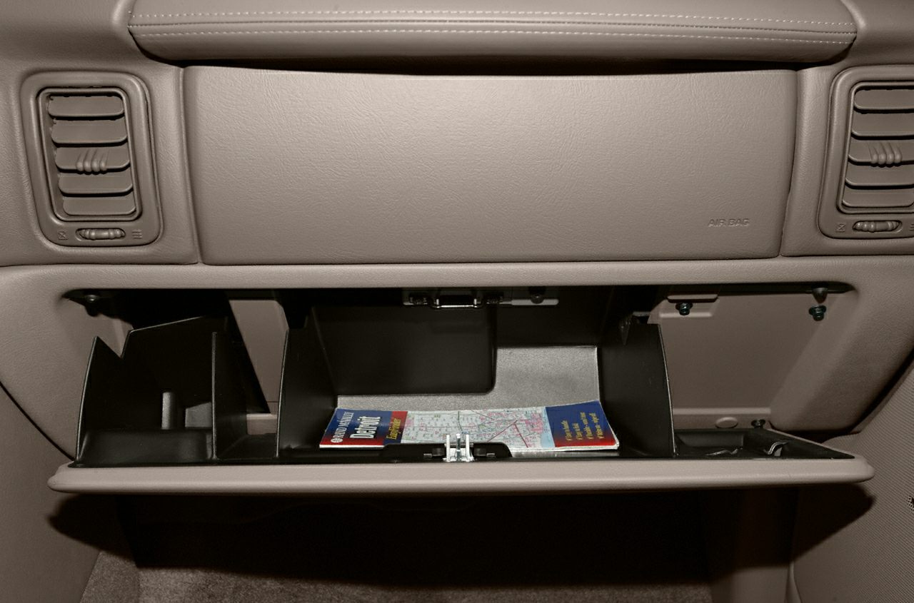 Open glove compartment with map inside, flanked by air vents