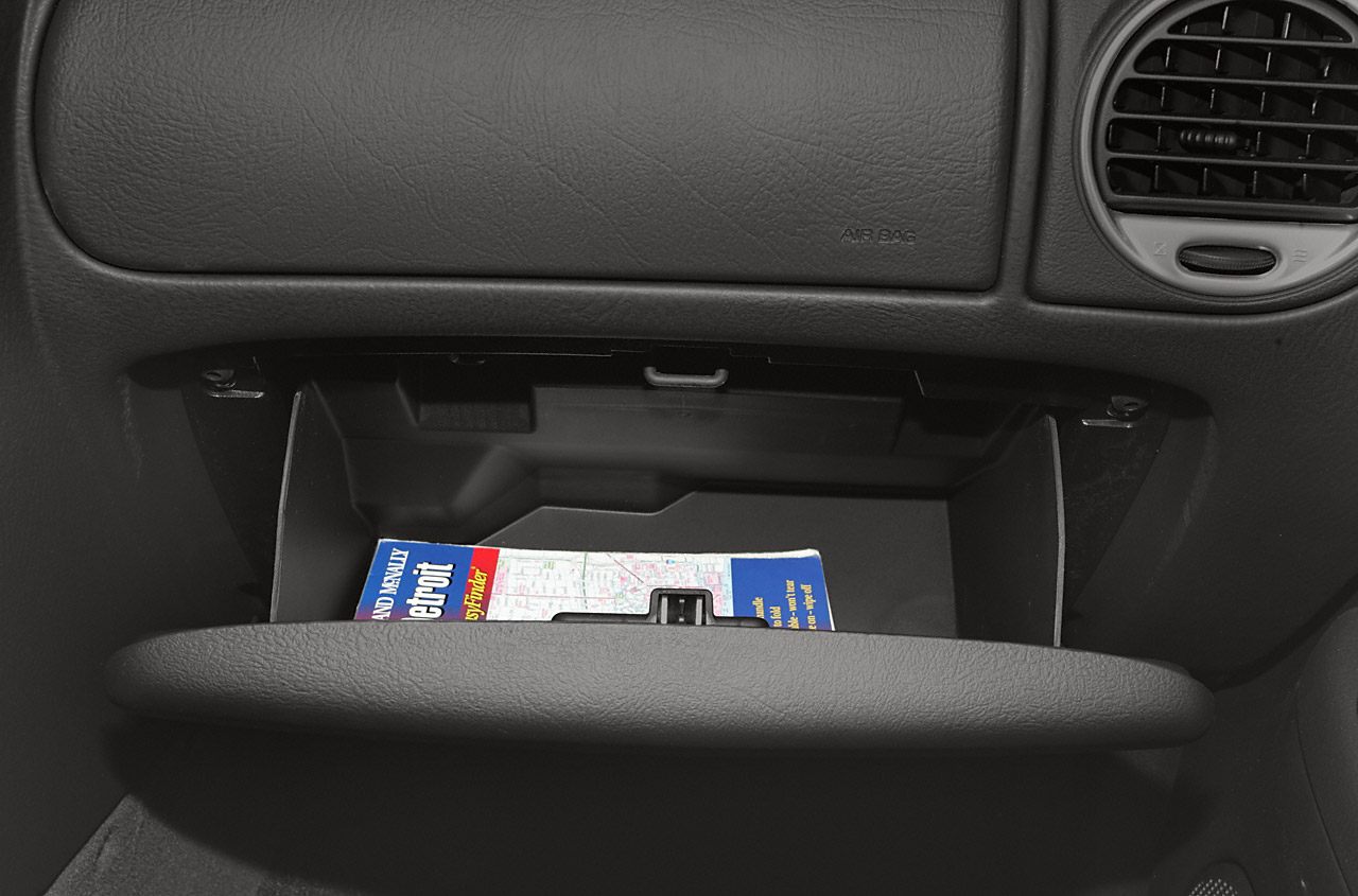 Glove compartment open with map inside, black dashboard and air vent