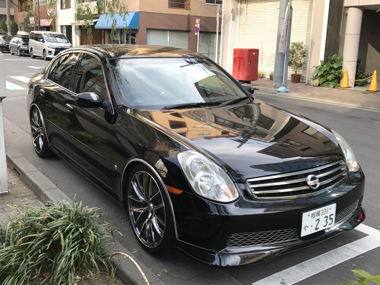 Black sedan with custom multi-spoke alloy wheels front side view
