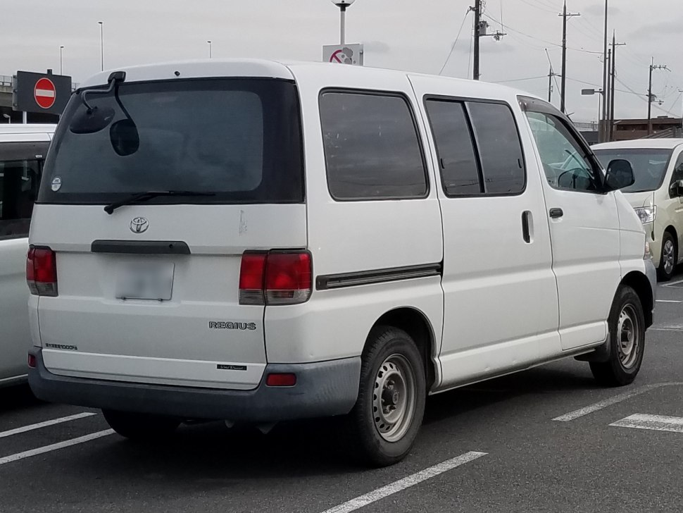 Rear and side view of a boxy white van with sliding side door and rear windshield wiper