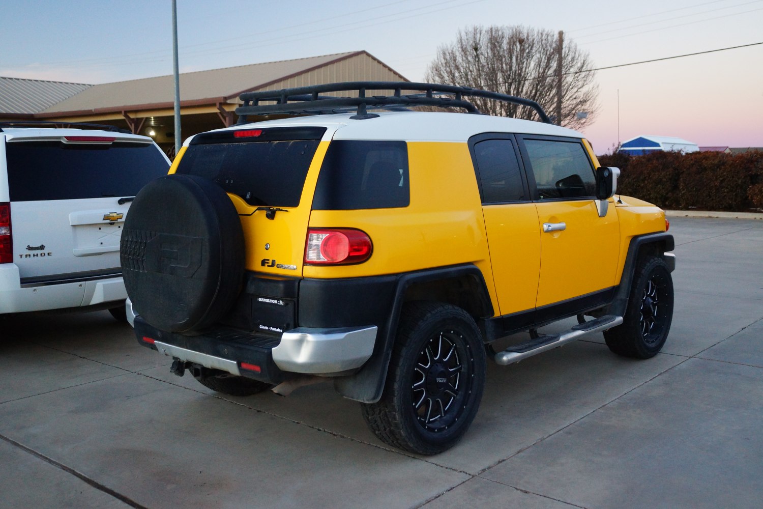 Yellow off-road SUV with roof rack and rear spare tire cover.