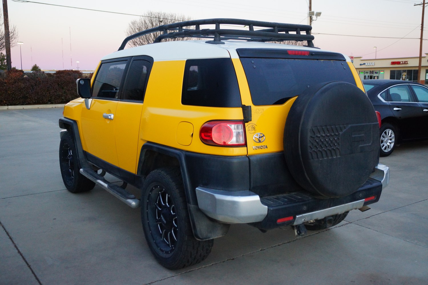 Yellow SUV rear with black roof rack and spare tire cover