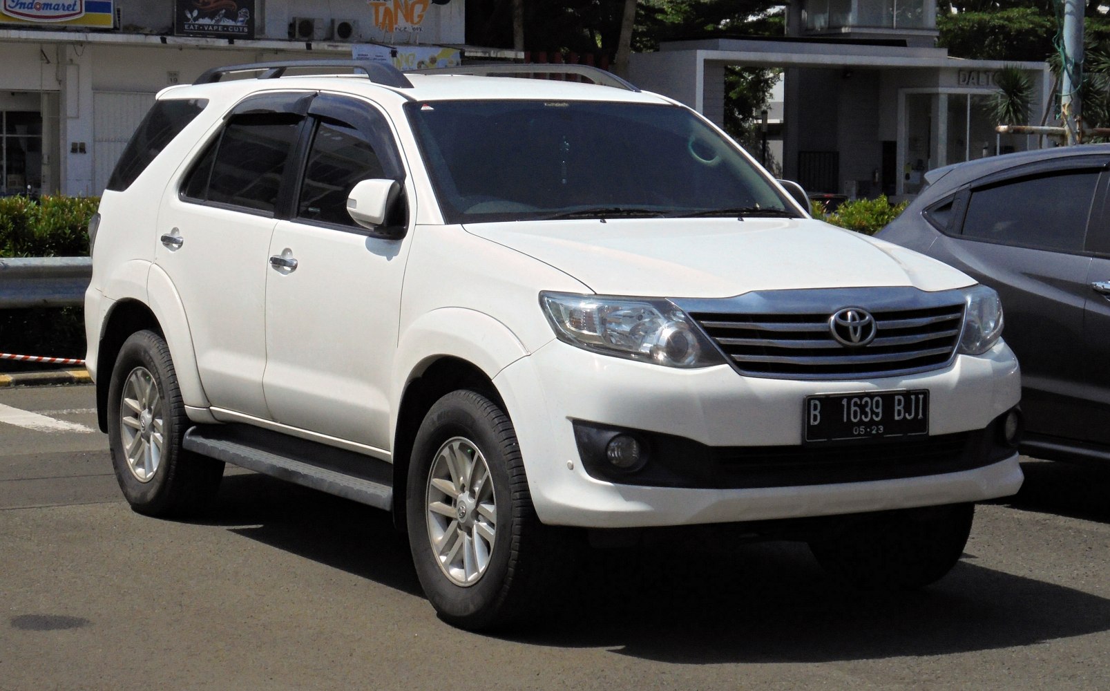 White mid-size SUV with frontal grille, side steps and roof rails