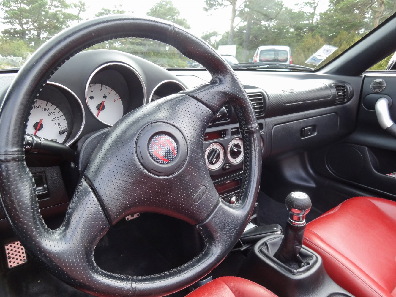 Steering wheel, dashboard, gear shifter, and red seats