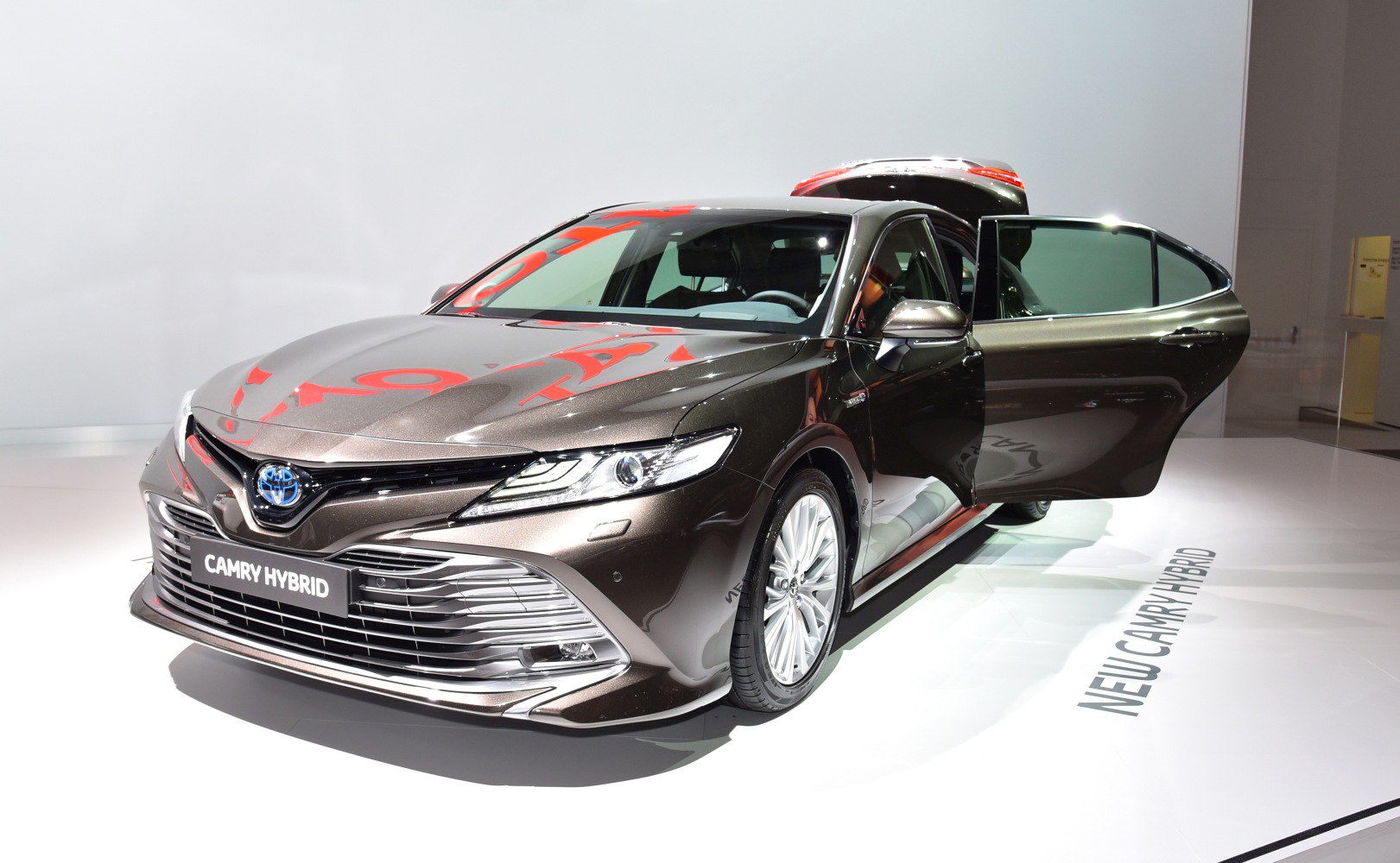 Front side view of a hybrid sedan with open door and alloy wheels