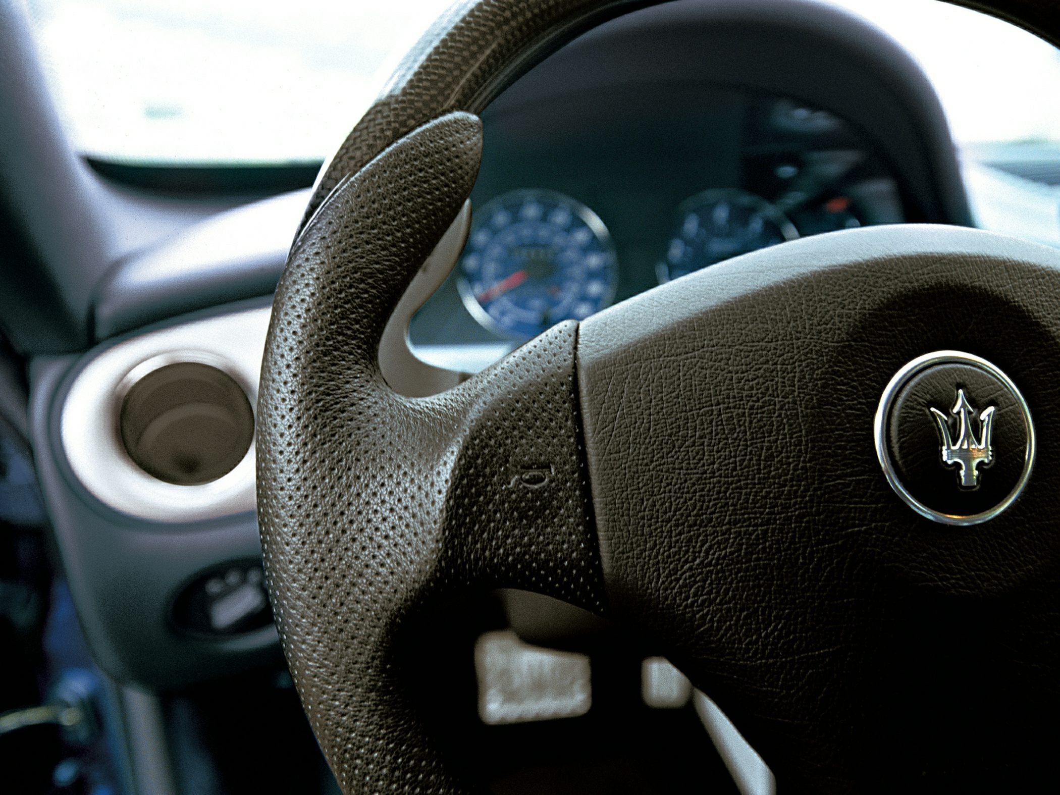 Close-up of steering wheel with trident emblem and leather grip