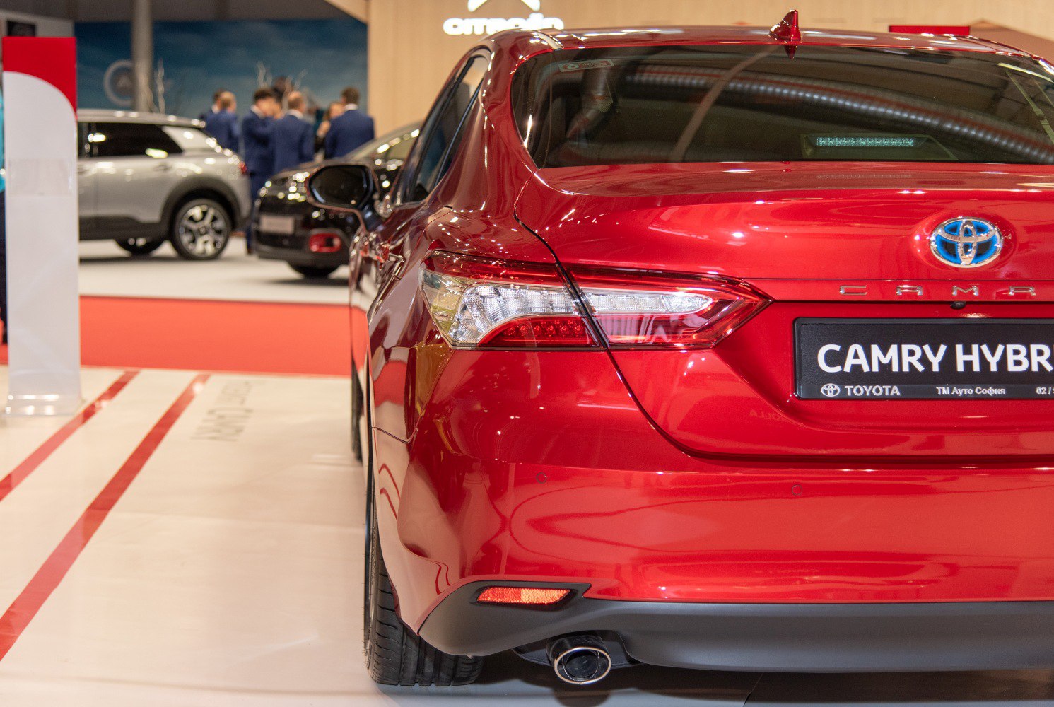 Red car rear with modern tail light and hybrid badge.