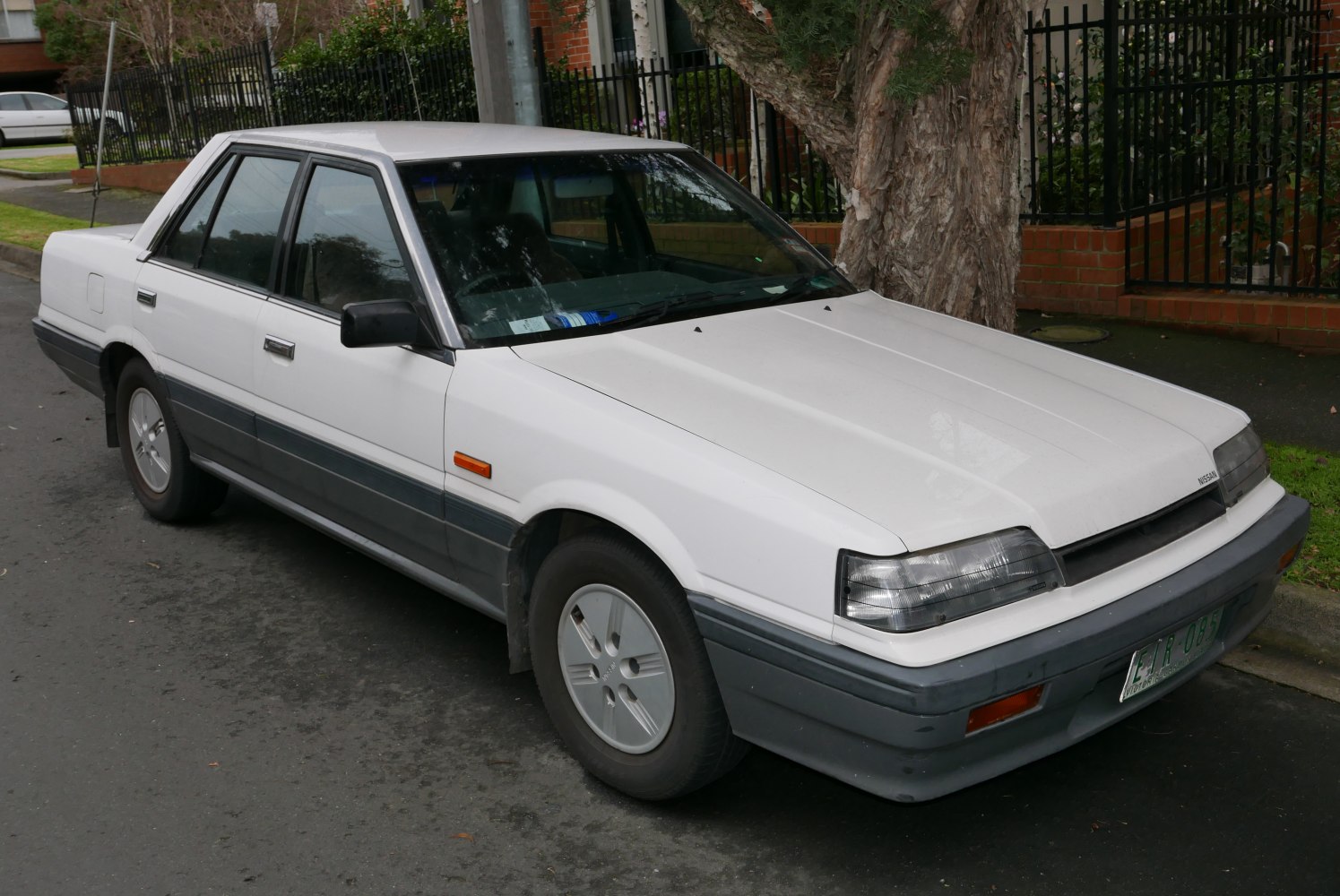 1980s boxy sedan with pop-up headlights and two-tone bumper