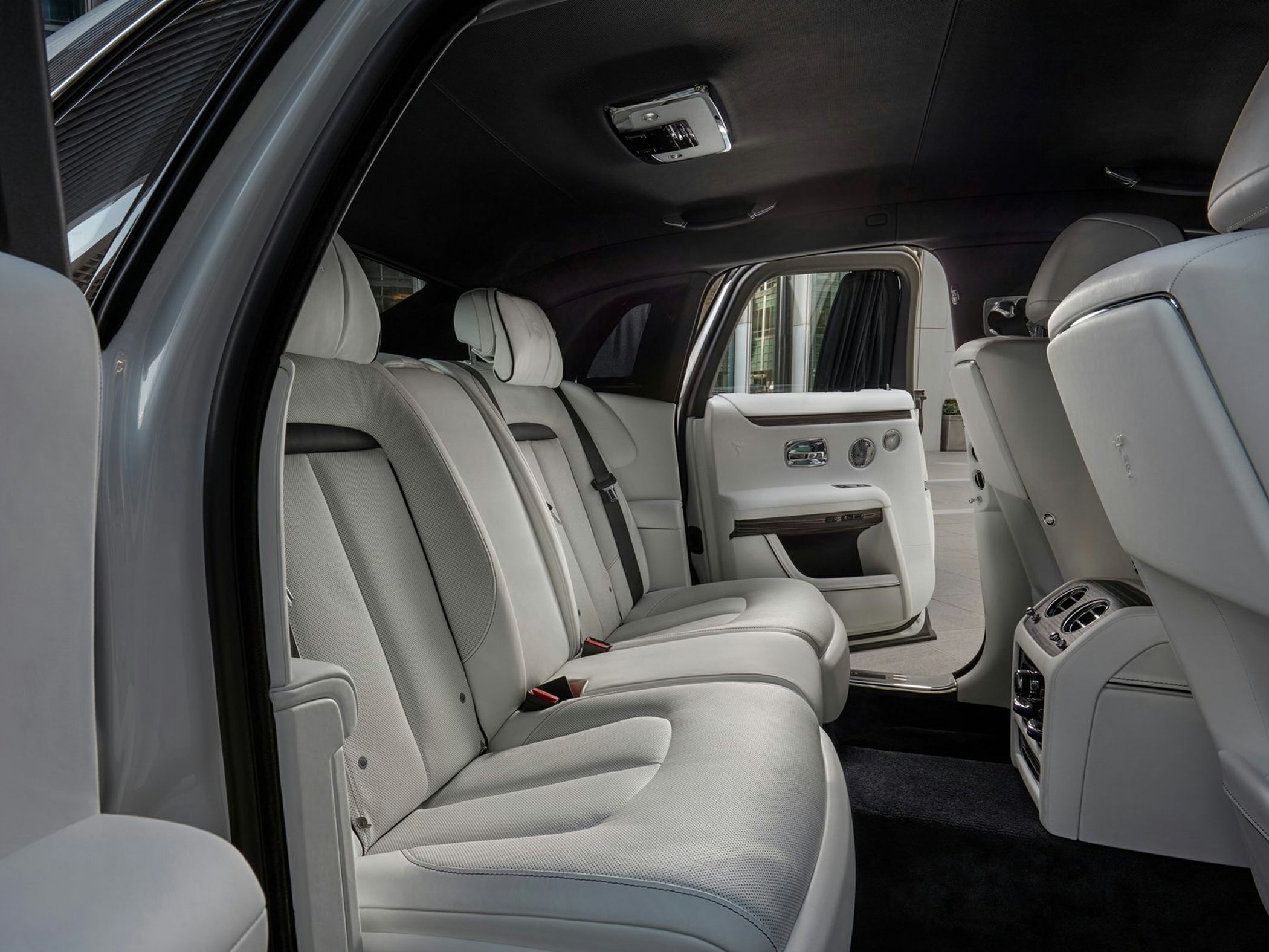 Spacious and luxurious rear seating with premium white leather upholstery and open rear door.