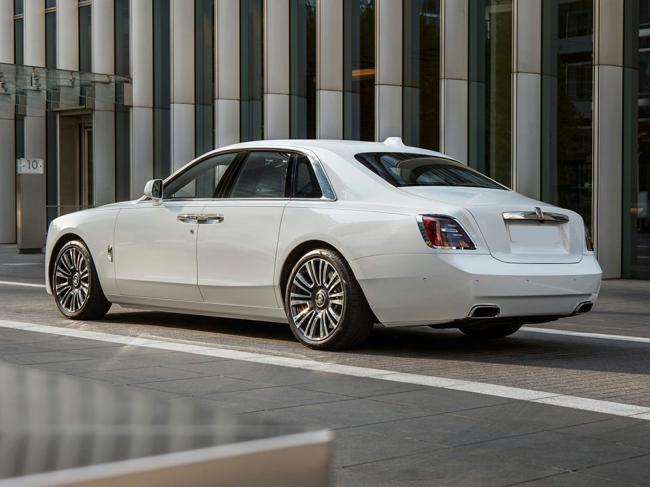 Rear-side view of white luxury sedan with multi-spoke alloy wheels