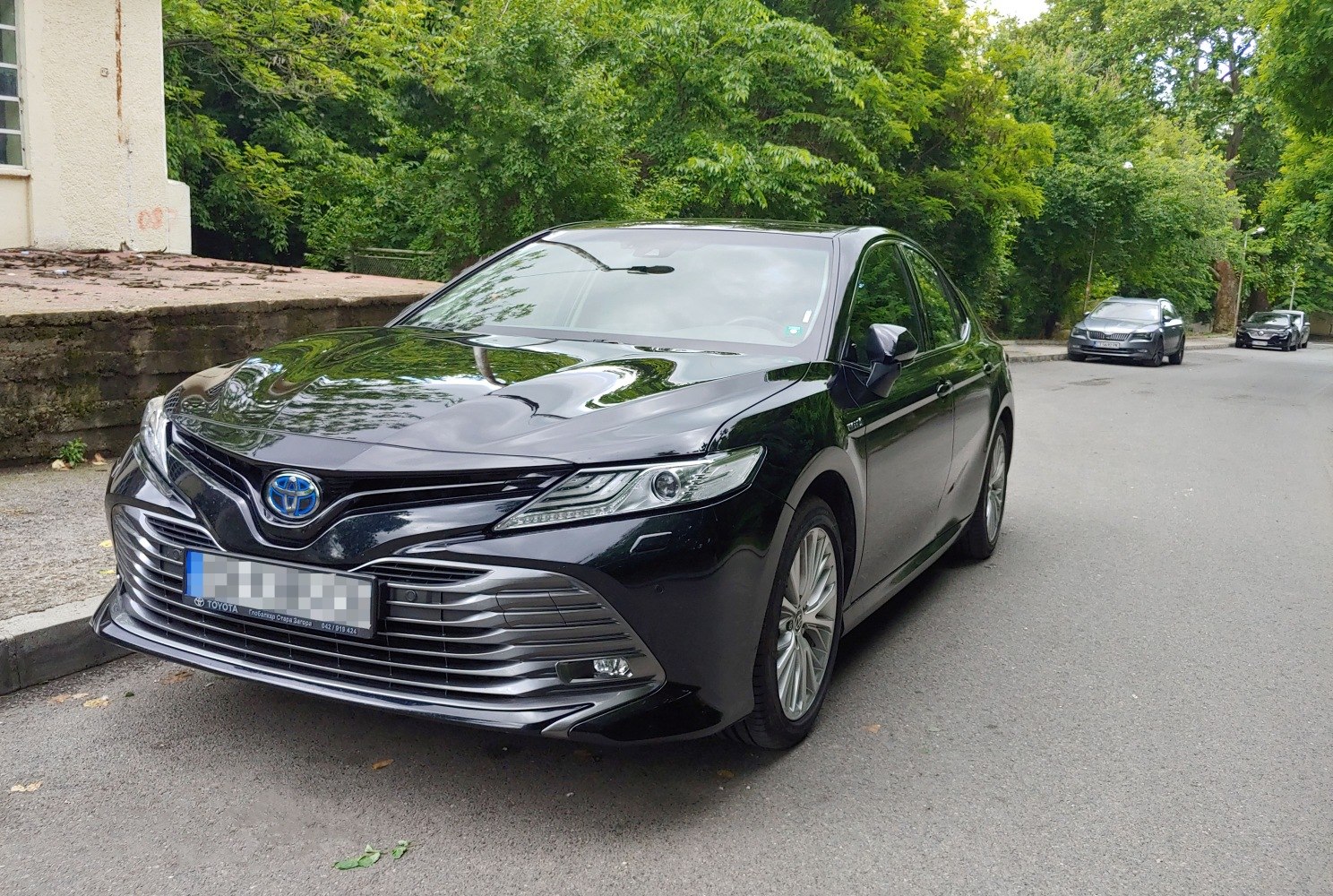 Sharp front grille and LED headlights with hybrid badge in black sedan.