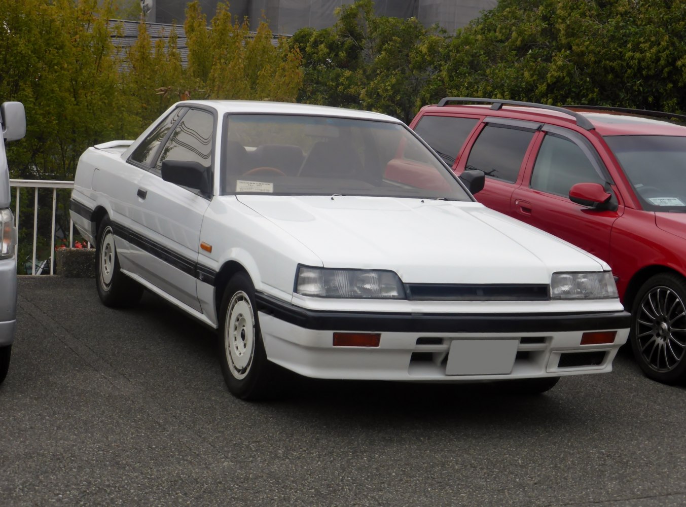 White two-door sports coupe with rectangular headlights and rear spoiler