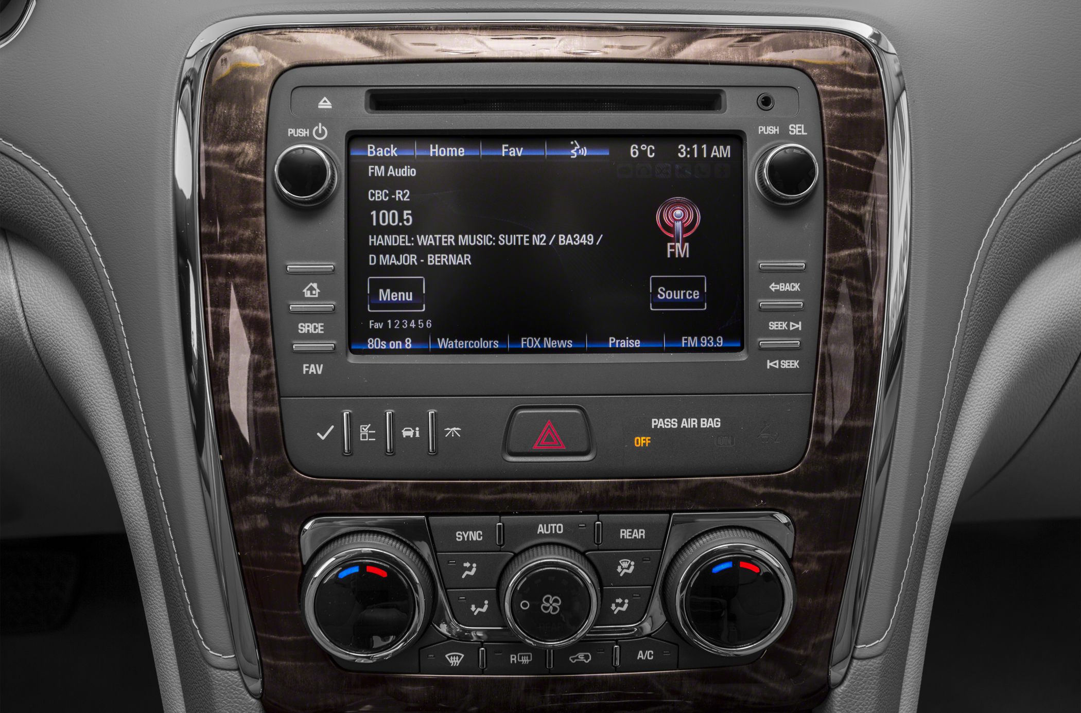 Infotainment display and climate control panel with wood trim and multiple control buttons