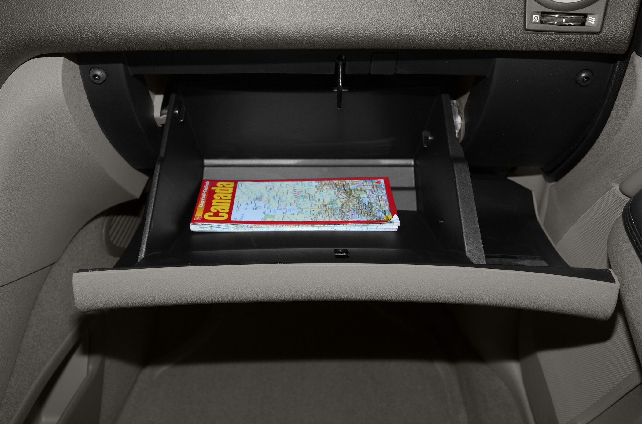 Open glove compartment with a folded Canada map inside.