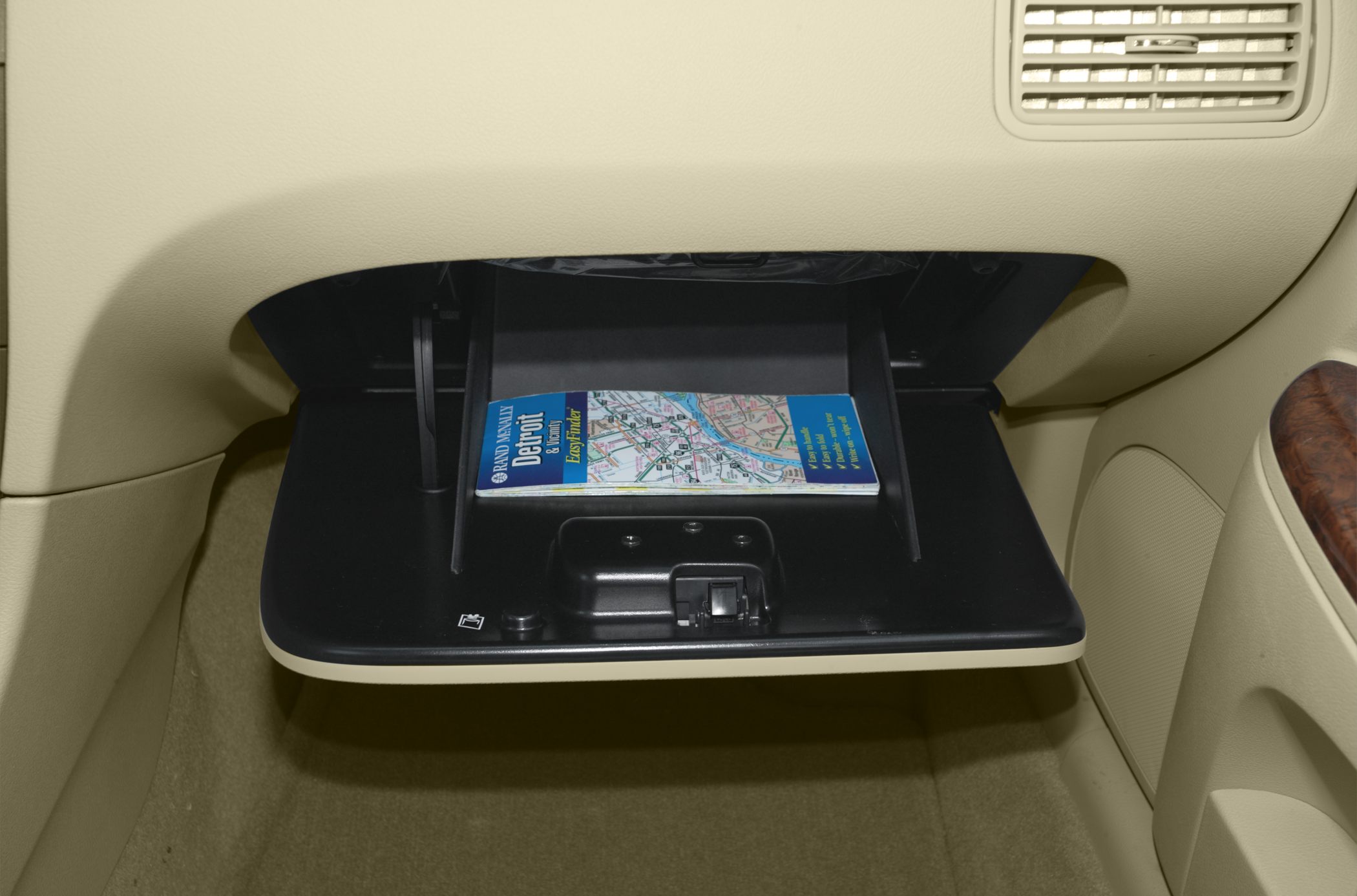 Open glove box compartment with beige interior and map inside