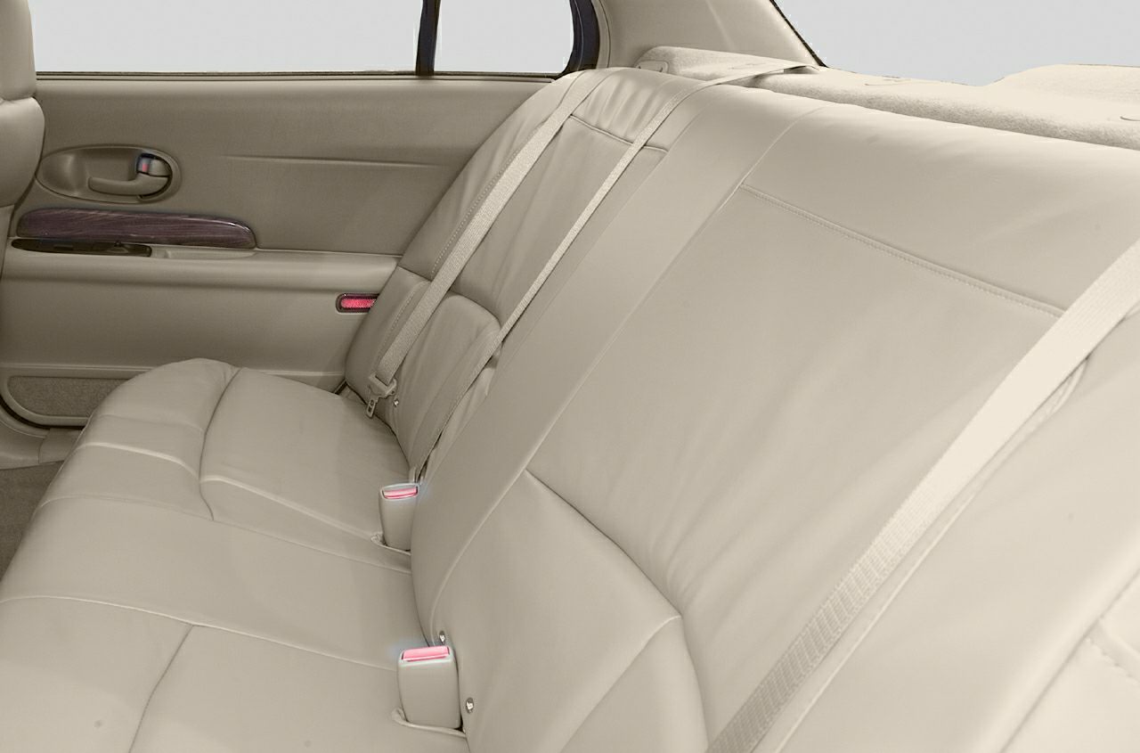 Beige leather rear seats with seatbelts and wood panel door trim
