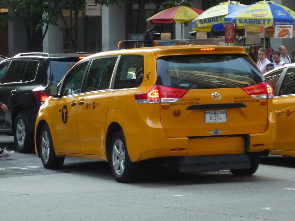 Yellow minivan taxi showing side and rear views with rear lights and sliding door