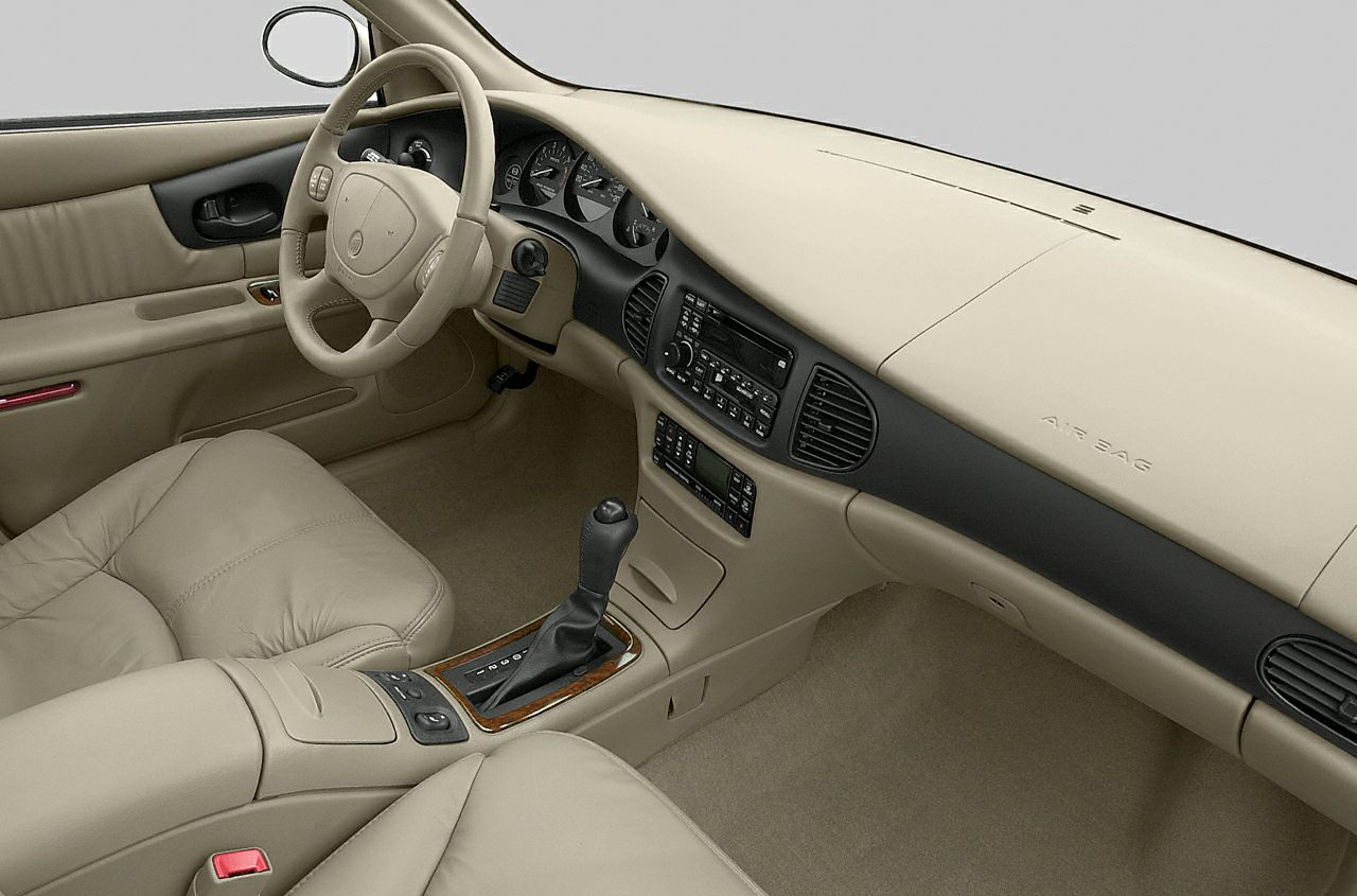 Beige car interior with classic steering wheel and automatic gear lever.