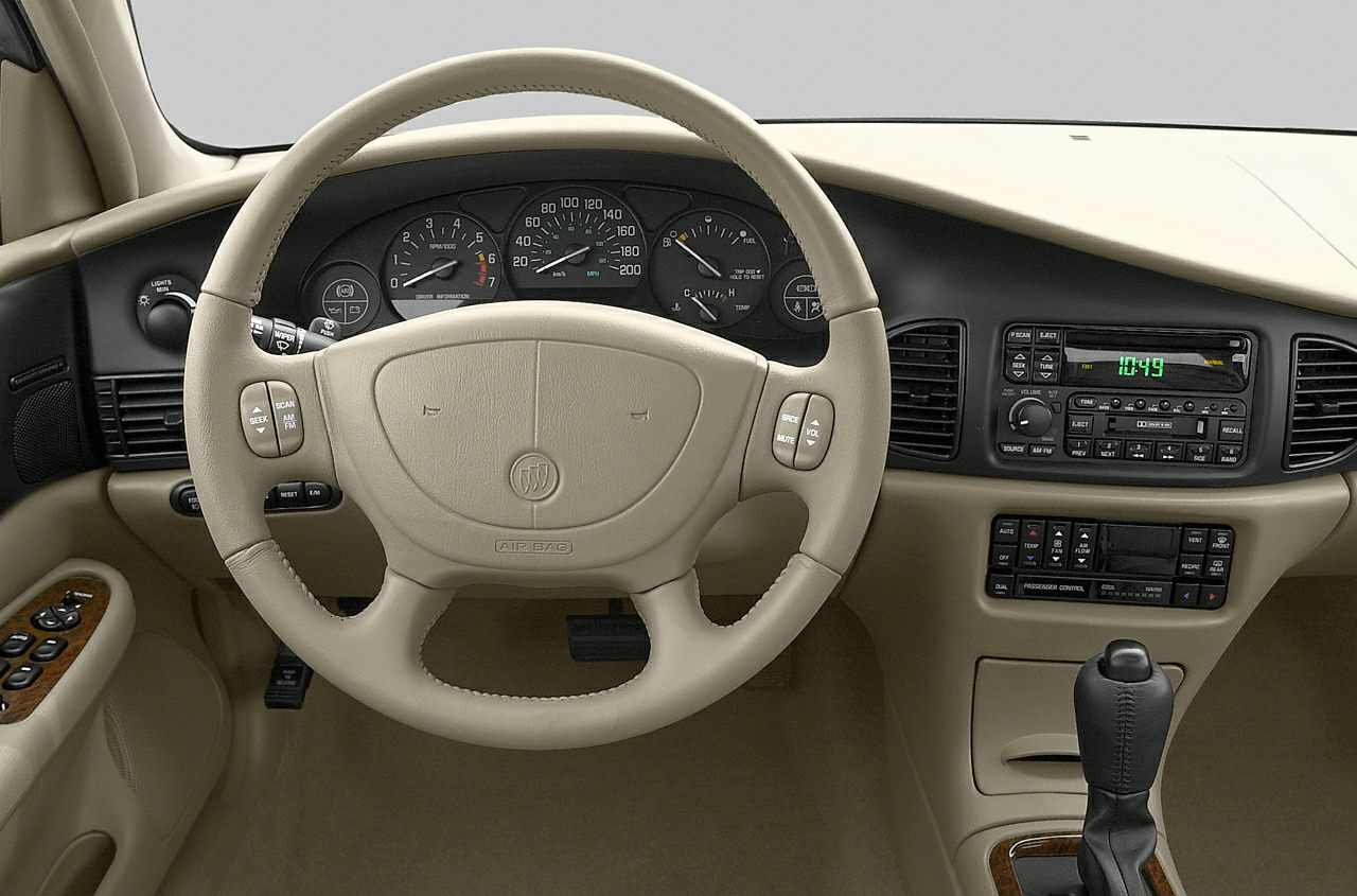 Beige steering wheel and dashboard with analog gauges and center console.