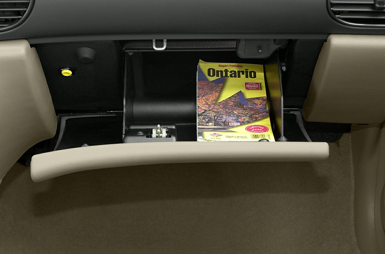 Open glove compartment with beige interior and map booklet