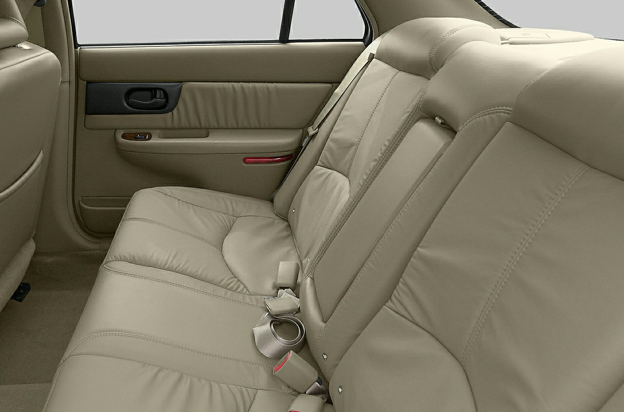 Beige leather rear seats and a door panel with armrest and controls