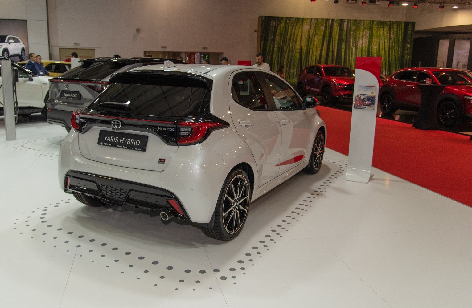 Rear angle of a white hybrid hatchback with sporty bumper and black roof