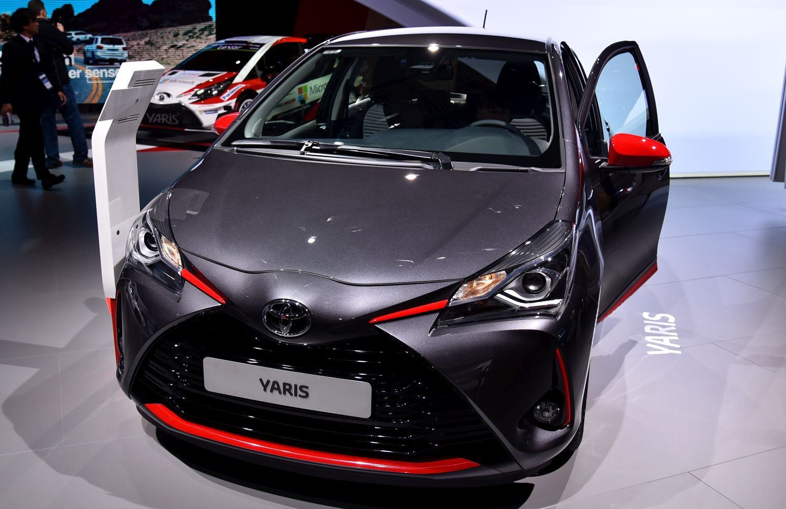 Front view with sharp headlights, black grille, red accents, and open door
