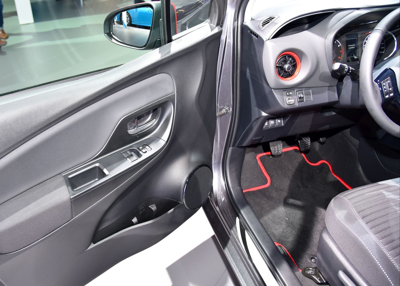 Driver side door panel and dashboard controls with pedals and floor mat detail