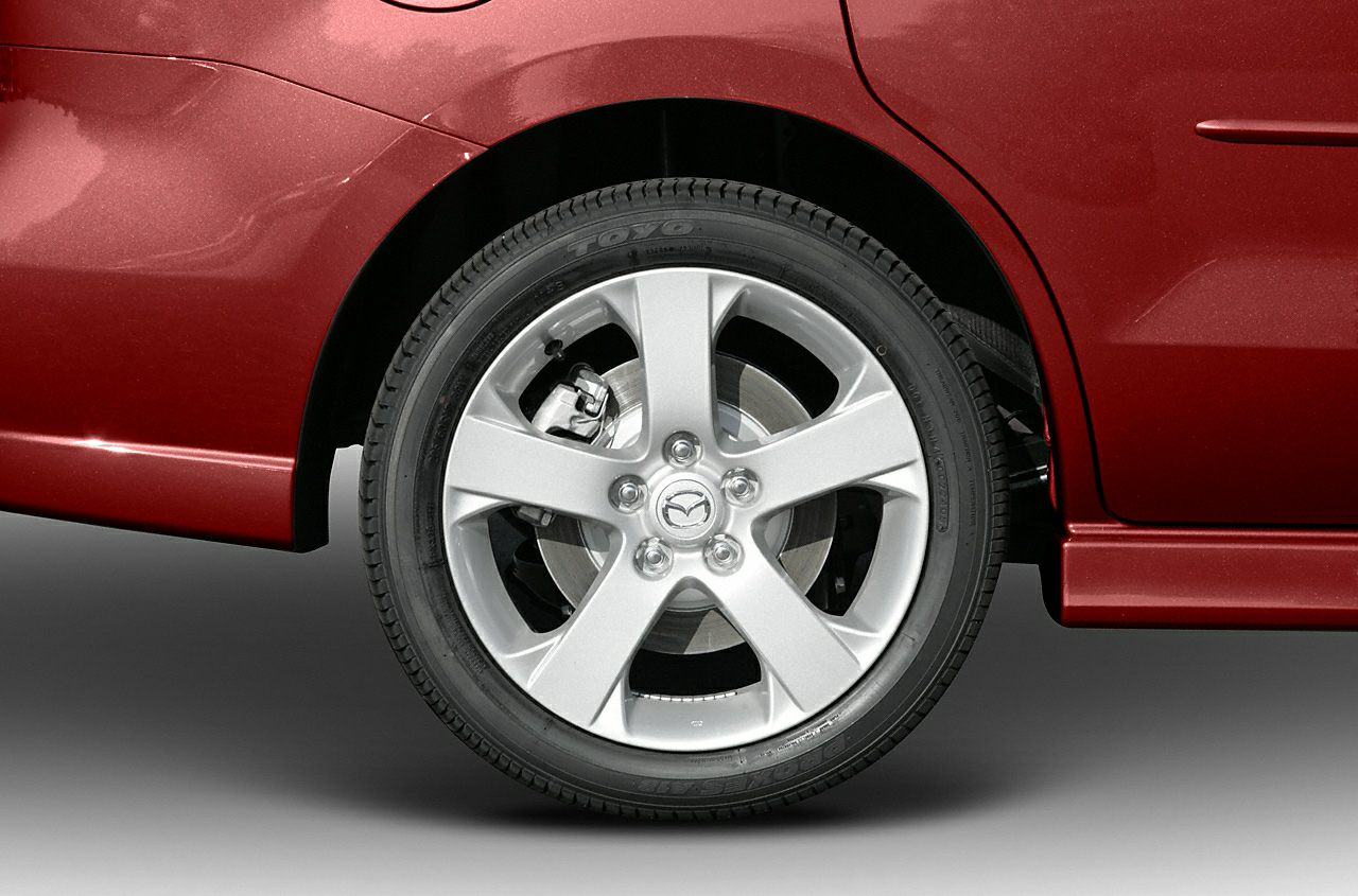 Close-up of alloy wheel, tire, and brake disc on red car body.