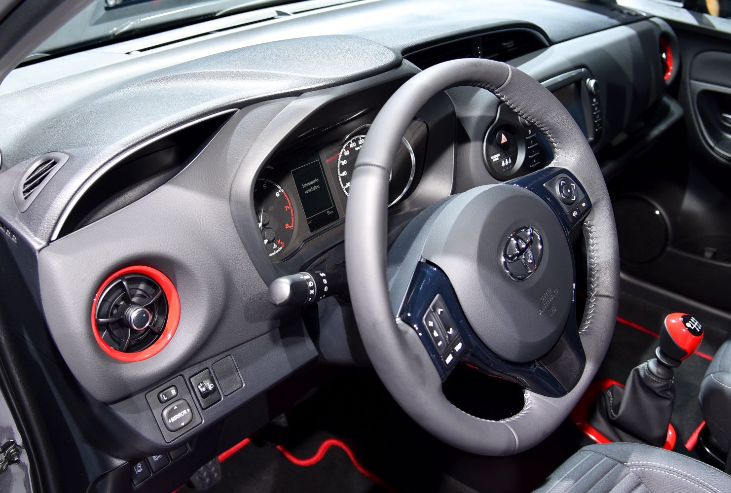 Dashboard with steering wheel and gear shift in compact car interior.